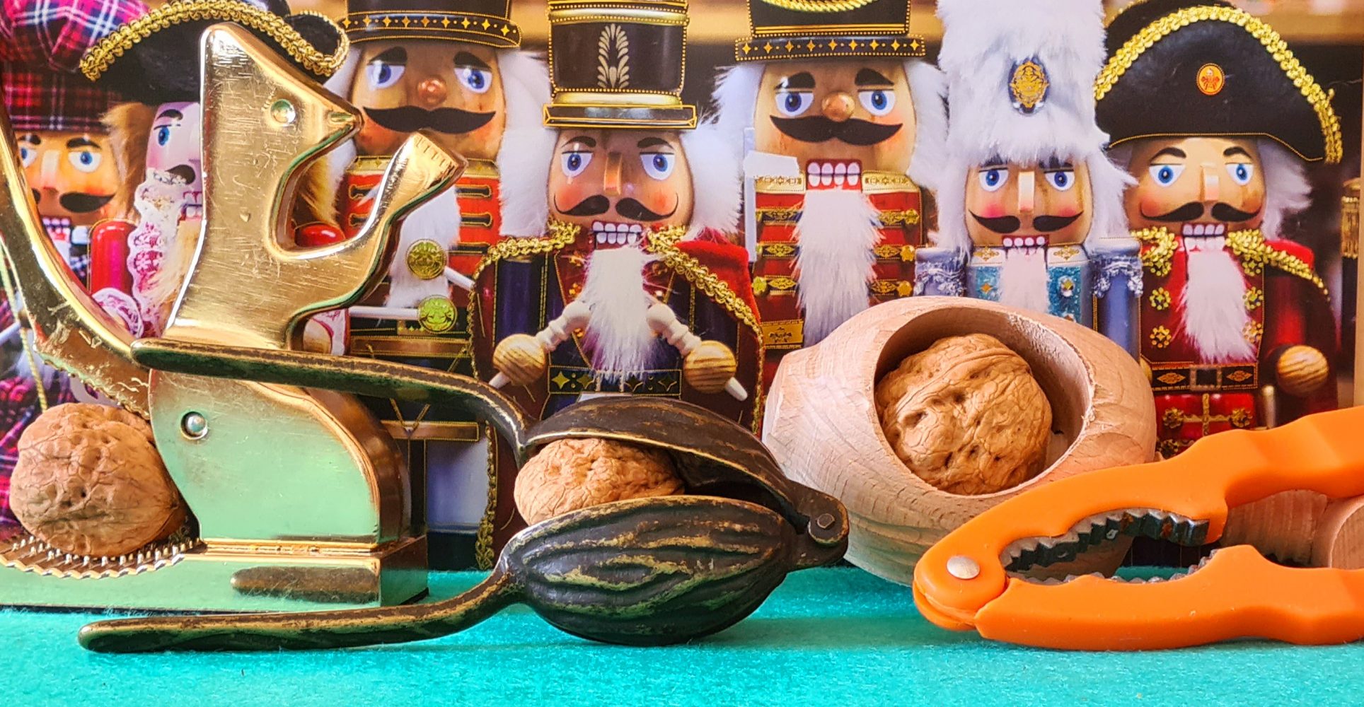 Quattro schiaccianoci disposti su un piano verde acqua. Dietro, una schiera di soldatini schiaccianoci tradizionali colorati e con folte barbe bianche - Four nutcrackers arranged on a teal surface. Behind them, a row of traditional colorful nutcracker soldiers with thick white beards