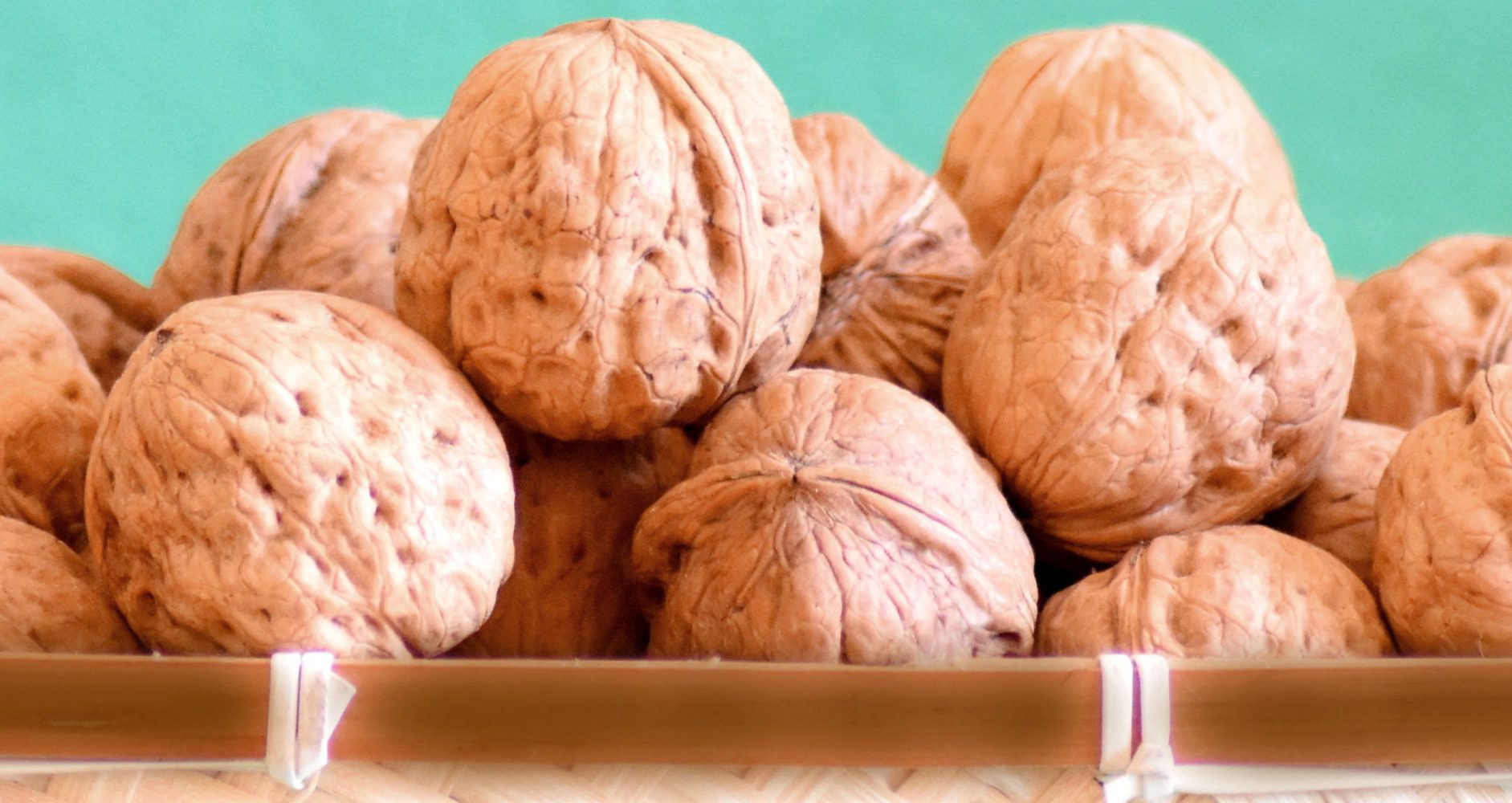 Primo piano di un gruppo di noci intere con guscio rugoso all'interno di un cesto - Close-up of a group of whole walnuts with rough shells inside a basket