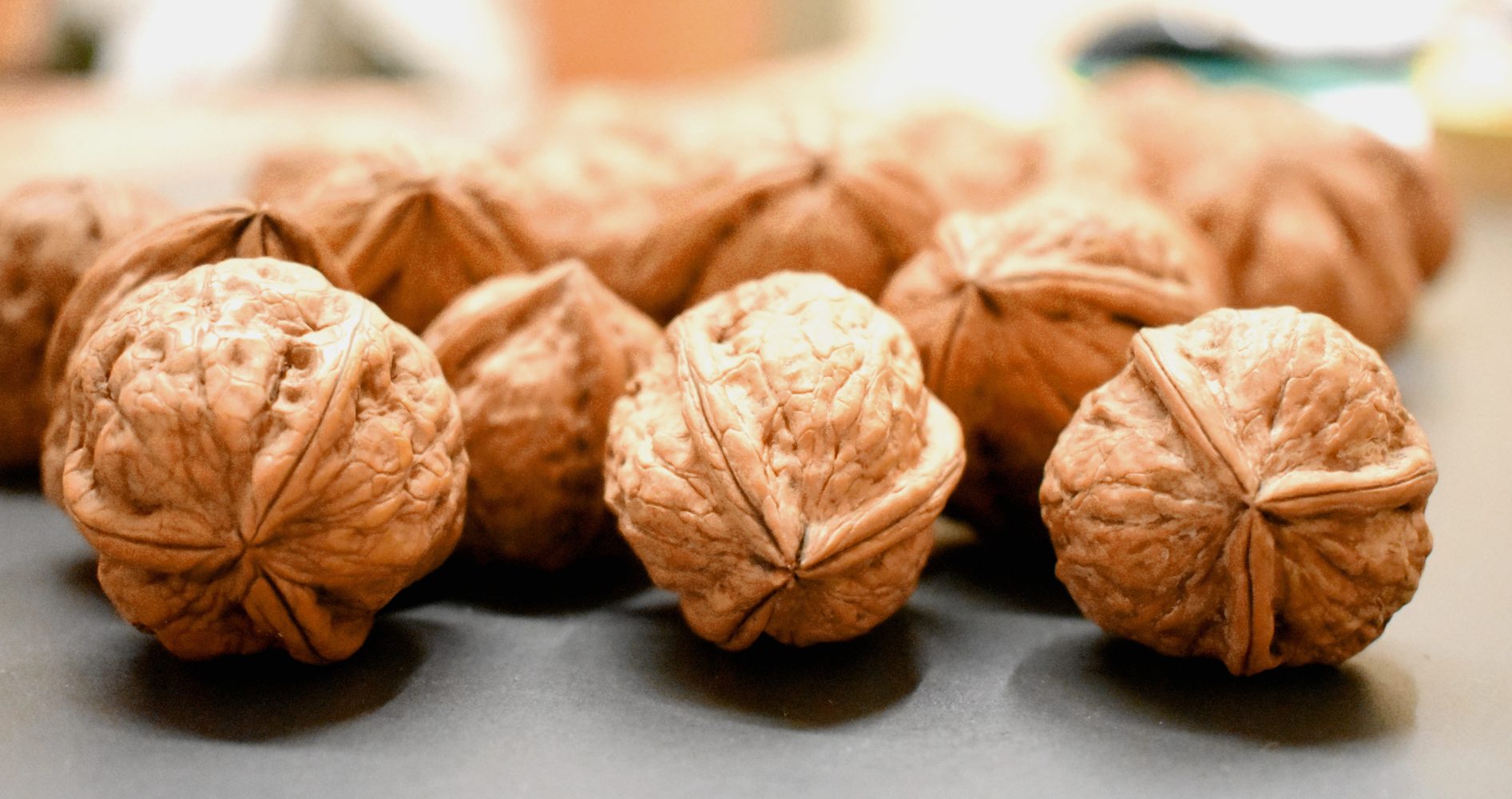 Primo piano di noci intere con guscio disposte su una superficie scura - Close-up of whole walnuts in their shells arranged on a dark surface