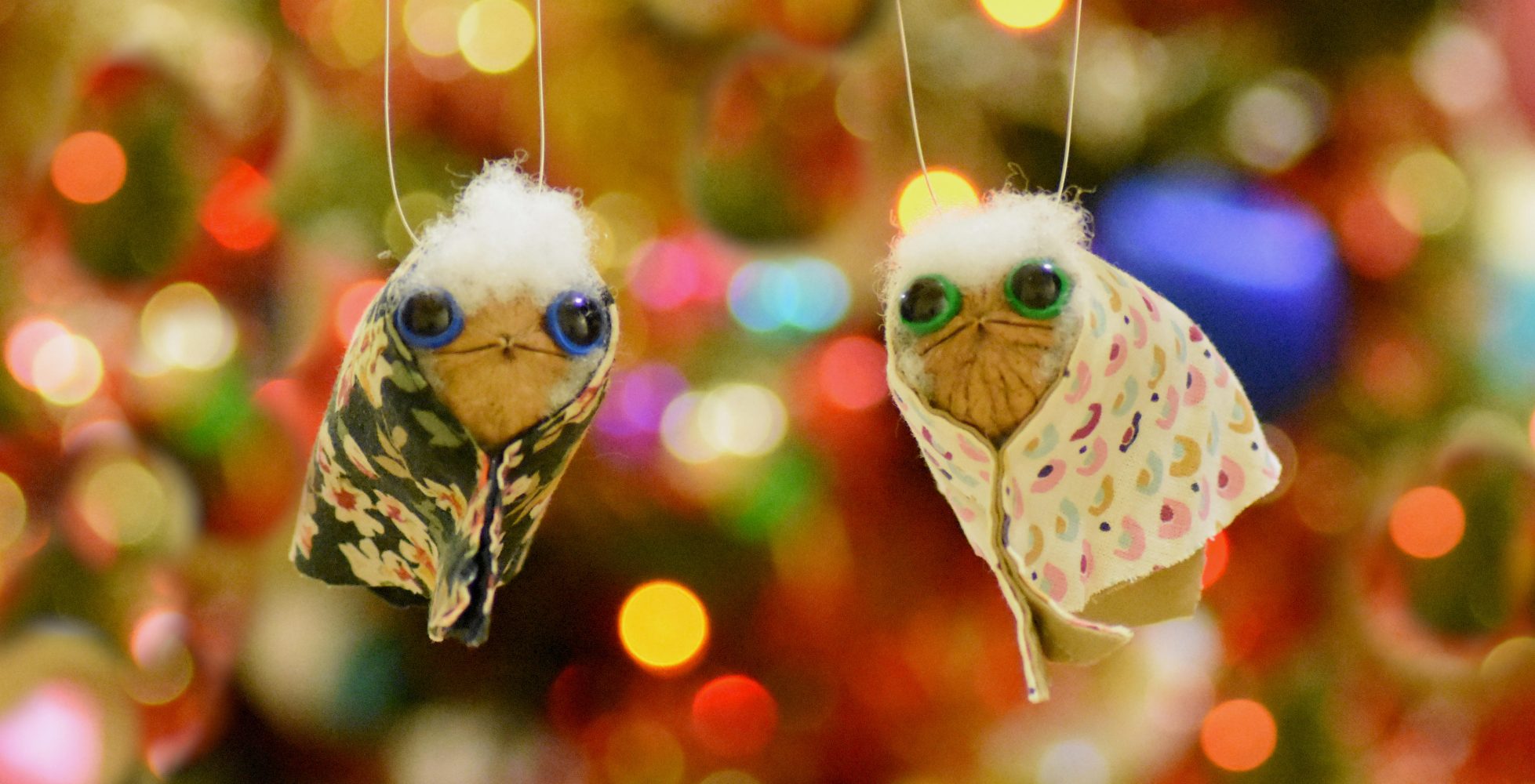 decorazioni realizzate con noci e stoffa, appesi come addobbi natalizi su uno sfondo di luci colorate - Decorations made with walnuts and fabric, hanging as Christmas ornaments against a background of colorful lights.